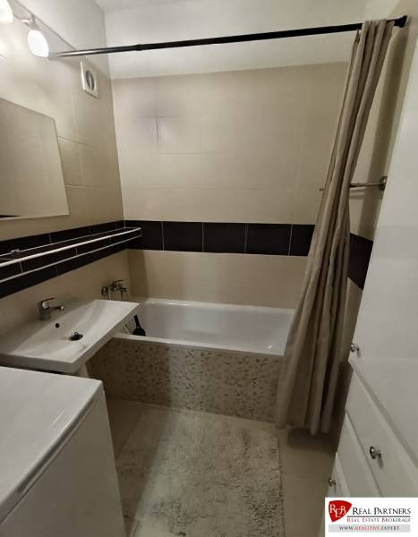 Badezimmer mit Duschvorhang, Badewanne und Waschbecken in einer 4-Zimmer-Wohnung.