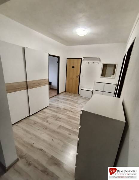 Ein Flur mit weißen Möbeln und einem Boden in Holzoptik in einer 4-Zimmer-Wohnung.
