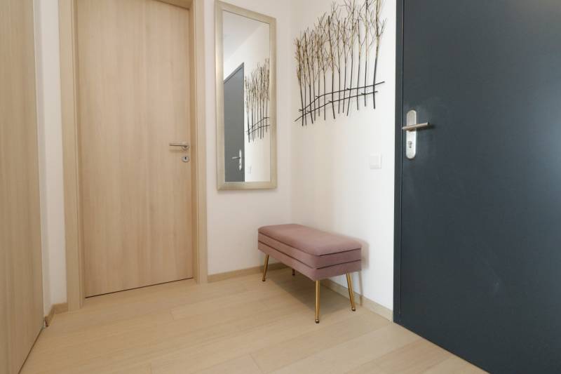 Flur in einer 2-Zimmer-Wohnung mit einem Boden in Holzoptik und einer Bank.