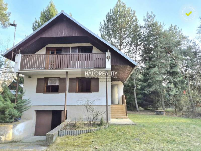 Eine Hütte in Borský Svätý Jur, umgeben von Grün und Bäumen, mit einem Holzbalkon.