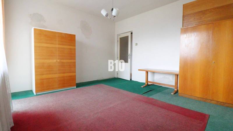 Ein Zimmer in einem Einfamilienhaus mit Teppichen, zwei Schränken und einem Tisch.