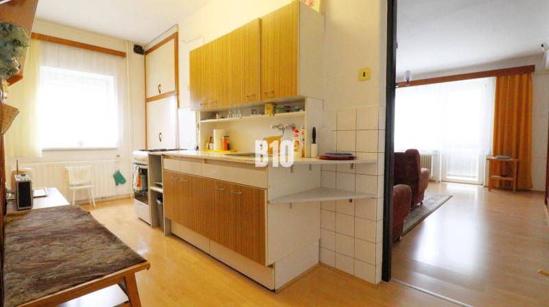 Küche in einem Einfamilienhaus mit Holzboden, verbunden mit dem Wohnzimmer.