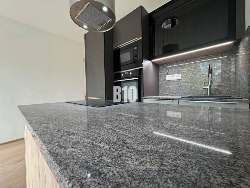 Küche in einer 2-Zimmer-Wohnung mit Marmorarbeitsplatte und moderner Ausstattung.
