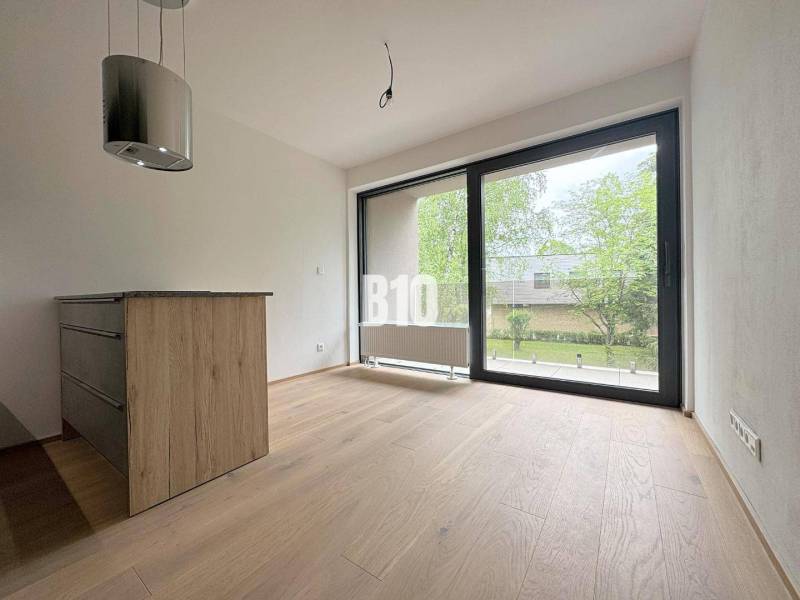 Innenraum einer 2-Zimmer-Wohnung mit Holzboden und großem Fenster mit Blick ins Grüne.