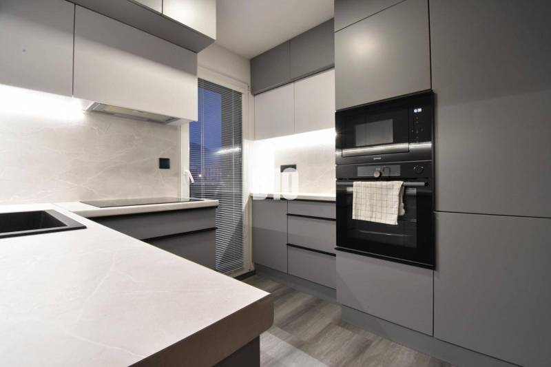 Küche in einer 4-Zimmer-Wohnung mit eingebauten Geräten und einem Boden in Holzoptik.