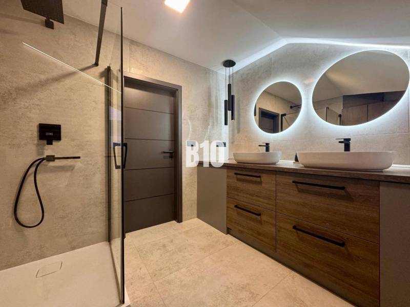 Badezimmer in einer 4-Zimmer-Wohnung mit zwei ovalen Spiegeln und einer Duschkabine.