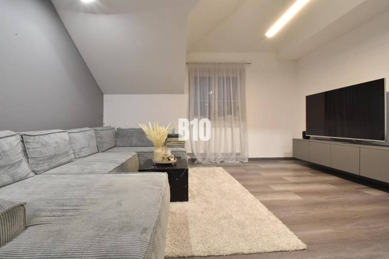 Wohnzimmer mit Ecksofa, Fernseher und Holzboden in einer 4-Zimmer-Wohnung.