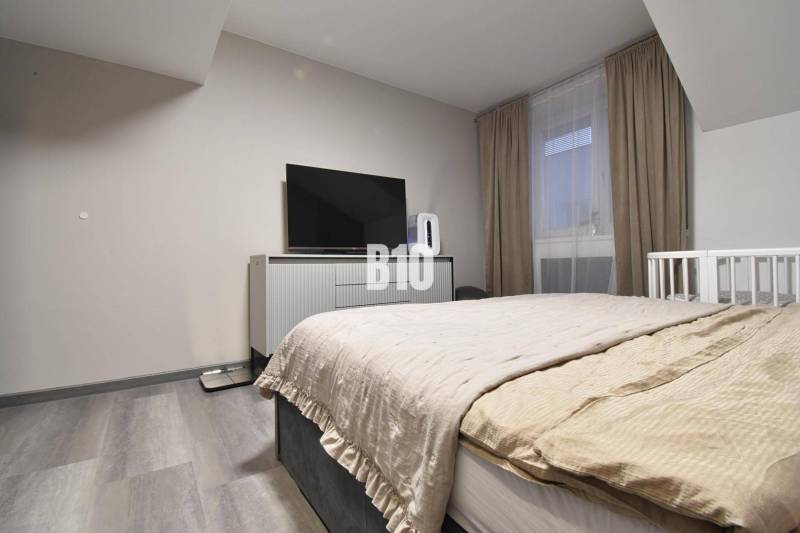 Schlafzimmer in einer 4-Zimmer-Wohnung mit Fernseher, Bett und Holzboden.