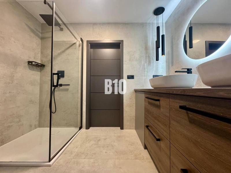 Badezimmer in einer 4-Zimmer-Wohnung mit offener Dusche und Boden in Holzoptik.