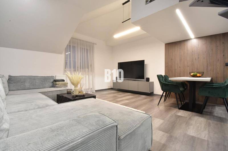 Wohnzimmer in einer 4-Zimmer-Wohnung mit Sofa, Fernseher und Holzboden.