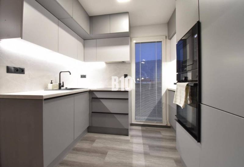Stilvolle Küche mit grauen Möbeln in einer 4-Zimmer-Wohnung, Boden mit Holzdekor.