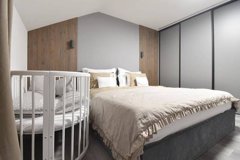 Schlafzimmer mit Bett, Kinderbett, Holzelementen und neutralen Farben in einer 4-Zimmer-Wohnung.