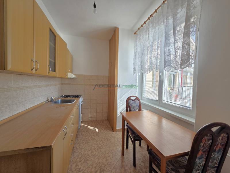 Küche mit Holzschränken, Tisch und zwei Stühlen in einer 3-Zimmer-Wohnung.