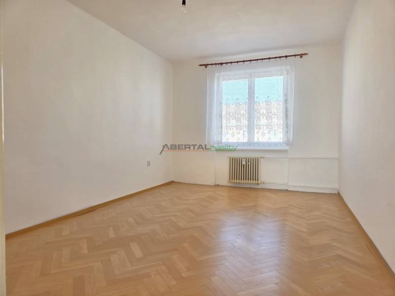 Ein leerer Raum mit einem Fenster und einem Boden in Holzoptik in einer 3-Zimmer-Wohnung.