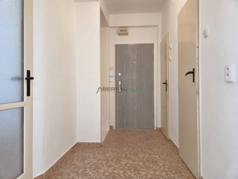 Ein Flur mit Fliesen, weiße Wände und mehrere Türen in einer 3-Zimmer-Wohnung.