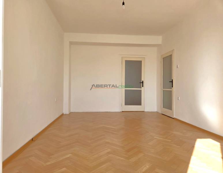 Ein Zimmer in der 3-Zimmer-Wohnung hat einen Boden mit Holzdekor und weiße Wände.