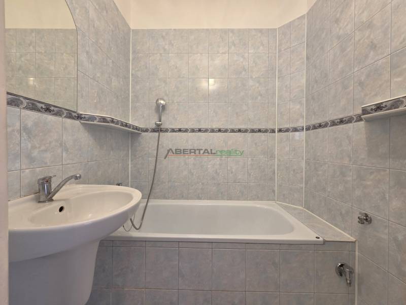 Badezimmer mit Badewanne in einer 3-Zimmer-Wohnung, gefliest mit hellen Keramikfliesen.