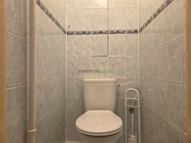 Toilette mit weißen Keramikfliesen in einer 3-Zimmer-Wohnung.