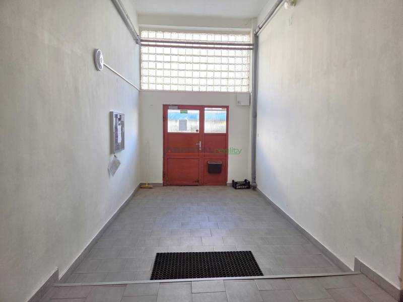 Ein Flur mit Fliesen, der zu einer roten Tür in einer 3-Zimmer-Wohnung führt.