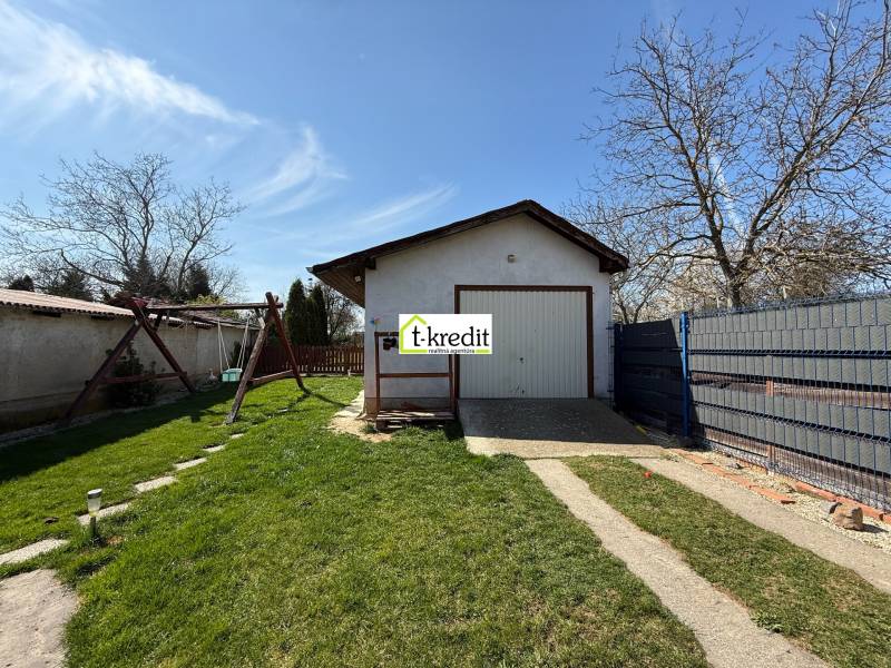 Ein Einfamilienhaus in Zlaté Moravce mit Rasen, Schaukel und Garage auf dem Grundstück.