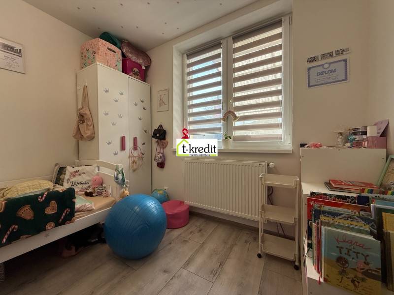 Kinderzimmer in einem Einfamilienhaus mit einem Boden in Holzoptik, voll mit Spielzeug und Büchern.