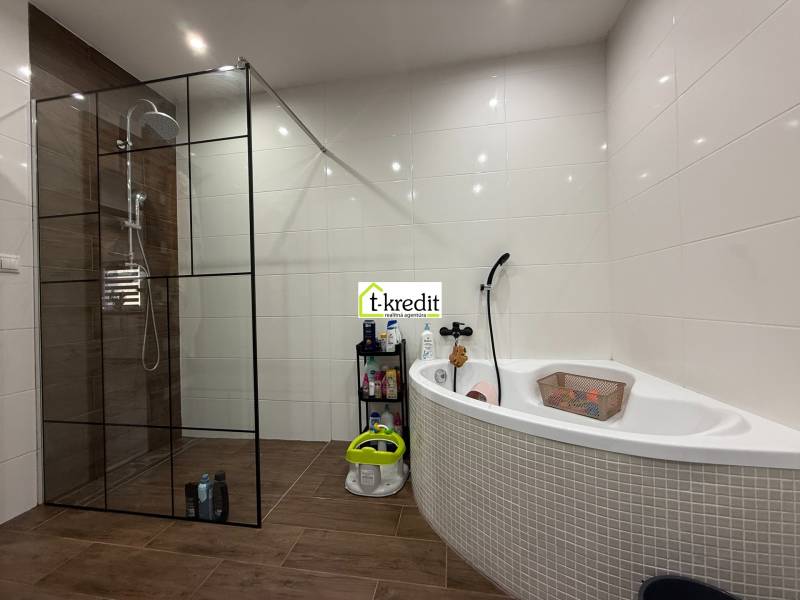 Ein Badezimmer in einem Einfamilienhaus mit Eckbadewanne und Duschkabine, Boden mit Holzdekor.