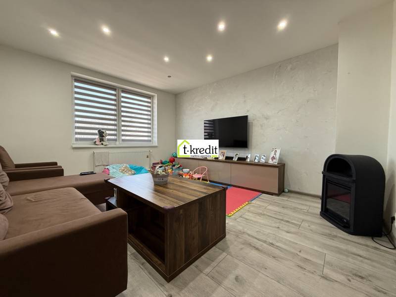 Wohnzimmer in einem Einfamilienhaus mit Sofa, Fernseher und Holzboden.