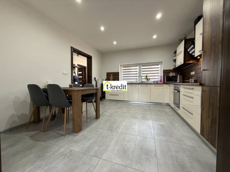 Eine Küche in hellen Farben mit eingebauten Geräten und einem Esstisch in einem Einfamilienhaus.