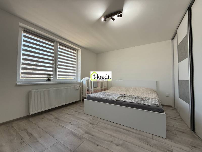 Helles Schlafzimmer in einem Einfamilienhaus mit Bett, Kleiderschrank und Boden in Holzoptik.