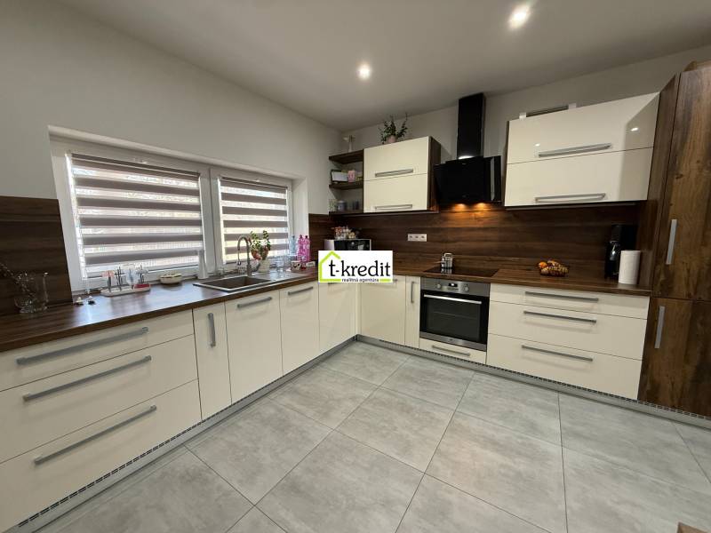 Küche in einem Einfamilienhaus mit großen Fenstern und eingebauten Geräten, Boden mit Holzdekor.