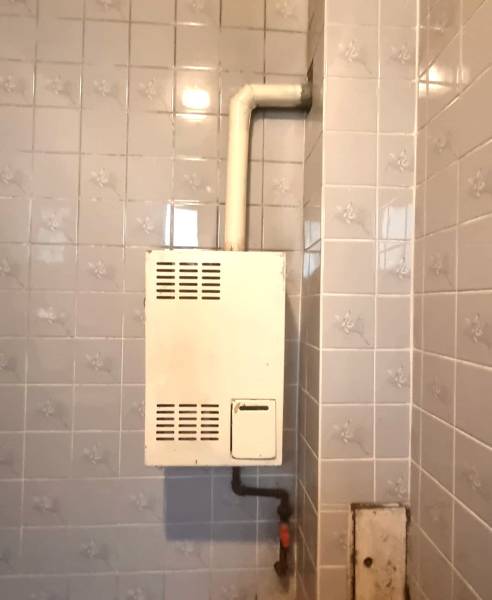 Badezimmer im Einfamilienhaus mit Gasheizung auf Fliesen.