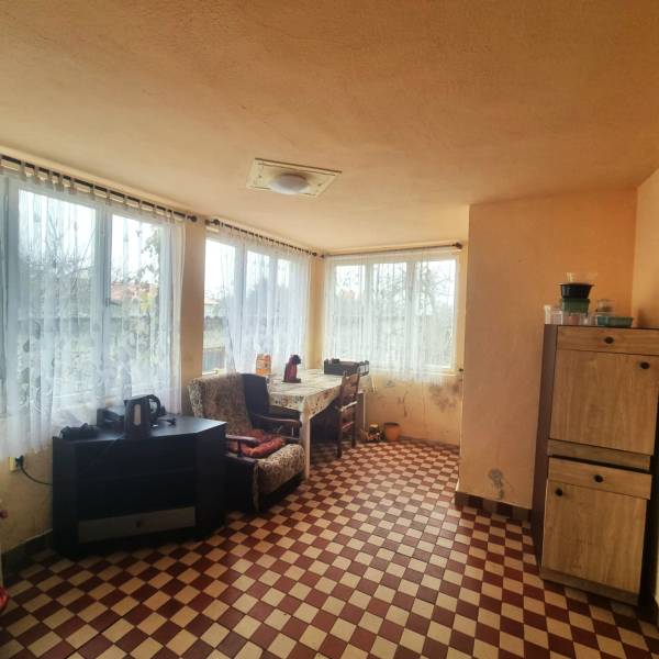 Ein Zimmer in einem Einfamilienhaus mit kariertem Boden, Möbeln und großen Fenstern mit Aussicht.