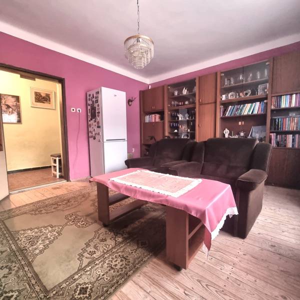 Wohnzimmer eines Einfamilienhauses mit rosa Wänden, Holzboden und Bücherregal.