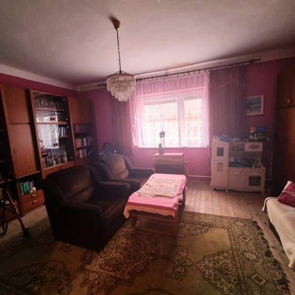 Wohnzimmer eines Einfamilienhauses mit rosa Wänden, Kronleuchter, Sofa und Holzboden-Dekor.