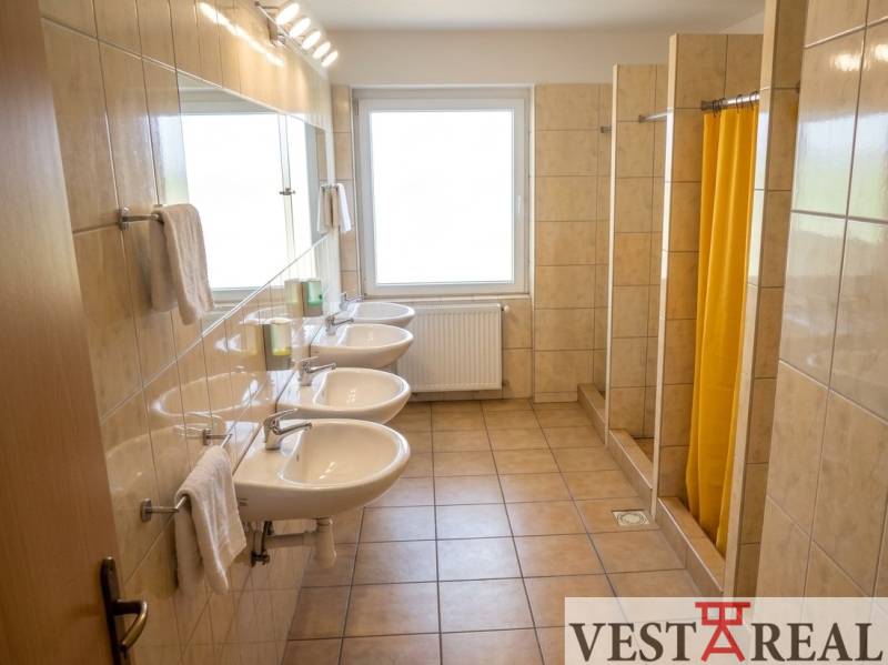 Das Badezimmer im Gebäude bietet Waschbecken und Duschen mit gefliestem Boden.