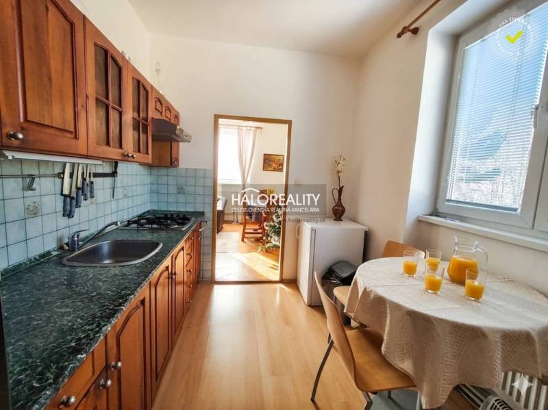 Küche in einer 3-Zimmer-Wohnung mit Holzschränken und einem Boden in Holzoptik.