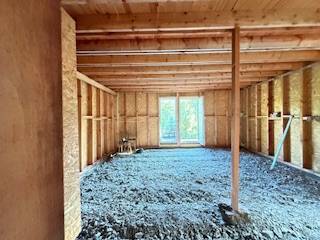 Unvollendetes Interieur einer Hütte mit Holzkonstruktion und einer Öffnung zur Terrasse.