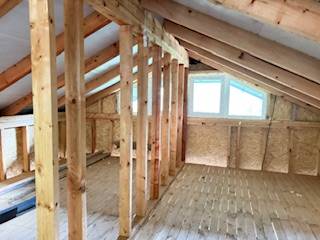 Dachboden mit Fenster, Holzbalken und Holzboden in einer Hütte.