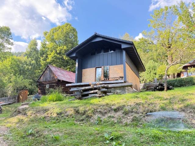 Eine Hütte in Horna Marikova, umgeben von Natur und Holzbauten, an einem sonnigen Tag.