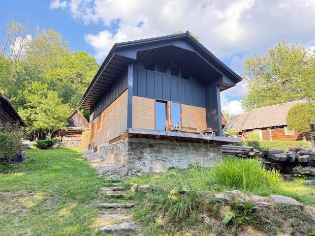 Eine Hütte im Dorf Horná Mariková mit steinernem Fundament und umgebender Natur.