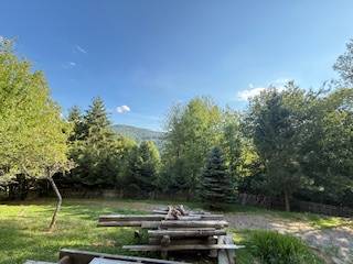 Die Natur in Horná Mariková mit einer Hütte, ein Tisch mit Bänken umgeben von Bäumen und Bergen.