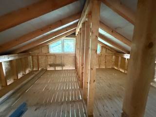 Dachboden eines Chalets mit Holzbalken und einem Boden in Holzoptik.