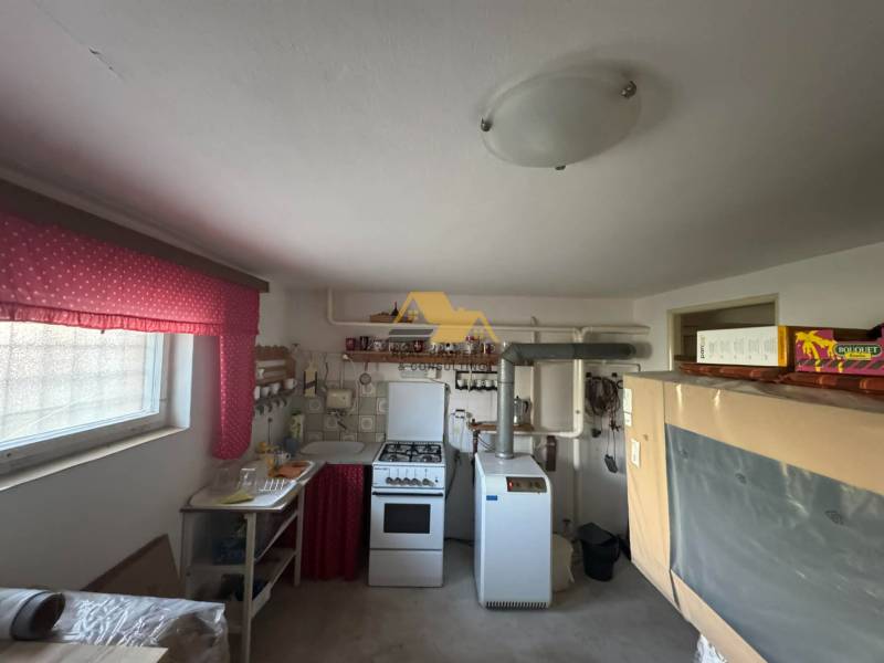 Küche in einem Einfamilienhaus mit einem älteren Herd und leuchtend roten Vorhängen.