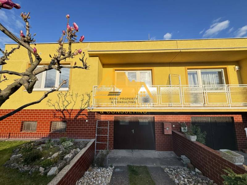 Ein Einfamilienhaus in der Stadt Nové Zámky in der Straße Nové Zámky mit gelber Fassade und Garten.