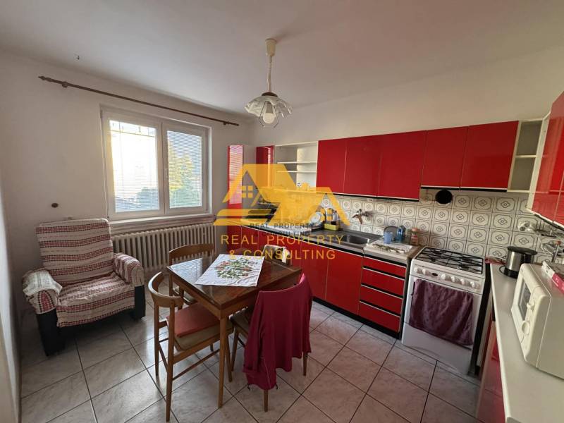 Küche mit roter Küchenzeile in einem Einfamilienhaus, ausgestattet mit Tisch und Stuhl.