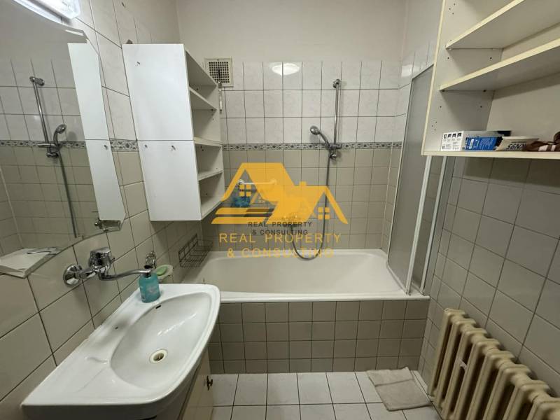 Badezimmer mit Badewanne, Waschbecken, weißen Schränken und Heizkörper in einem Einfamilienhaus.