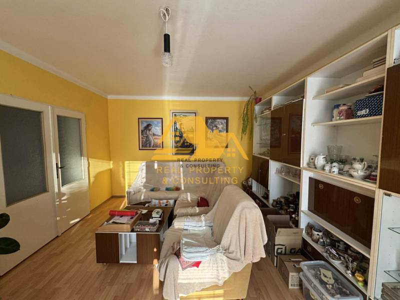 Wohnzimmer in einem Einfamilienhaus mit weißem Sofa, Holzboden, gelbe Wände.