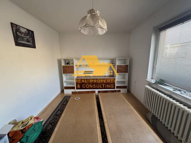 Ein Zimmer mit weißer Wand, Regalschrank und Holzboden in einem Einfamilienhaus.