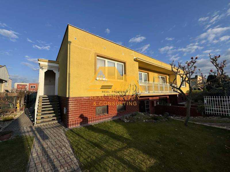 Gelbes Einfamilienhaus in Nové Zámky in einer Straße mit gepflegtem Garten und Gehweg.