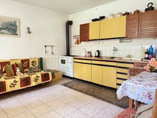 Eine Küche in einem Einfamilienhaus mit beigefarbenen Küchenschränken und einem Kachelofen.